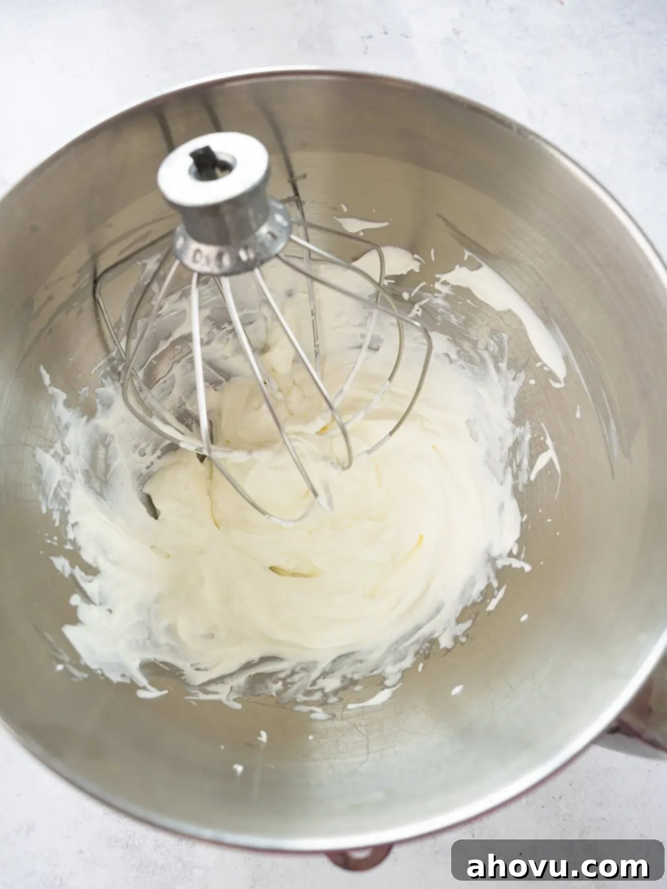 An overhead view of freshly whipped heavy cream in a mixing bowl, showing its fluffy, stiff-peaked texture.