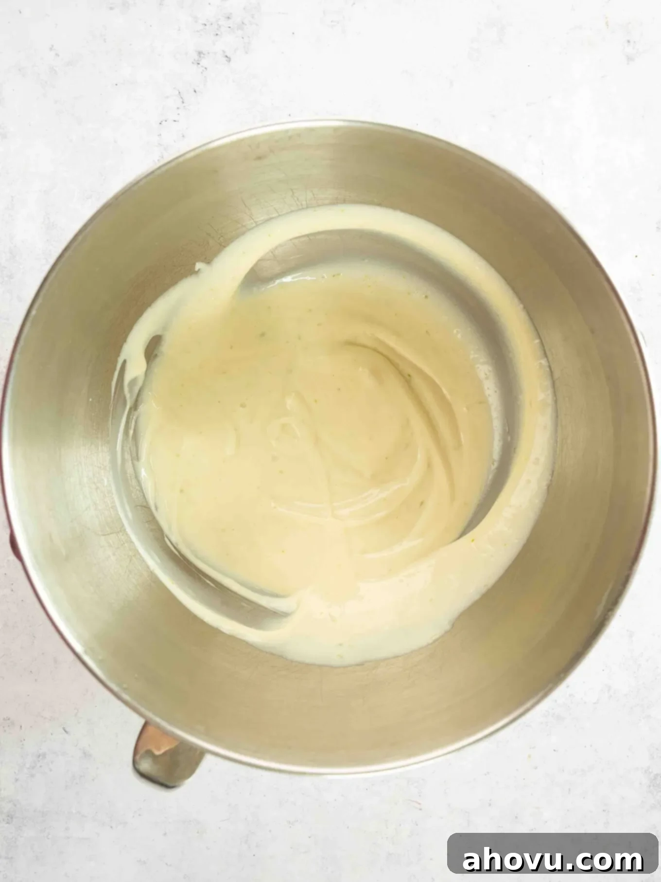 An overhead view of the vibrant key lime pie filling mixture in a mixing bowl, showcasing its smooth, creamy consistency before folding in whipped cream.