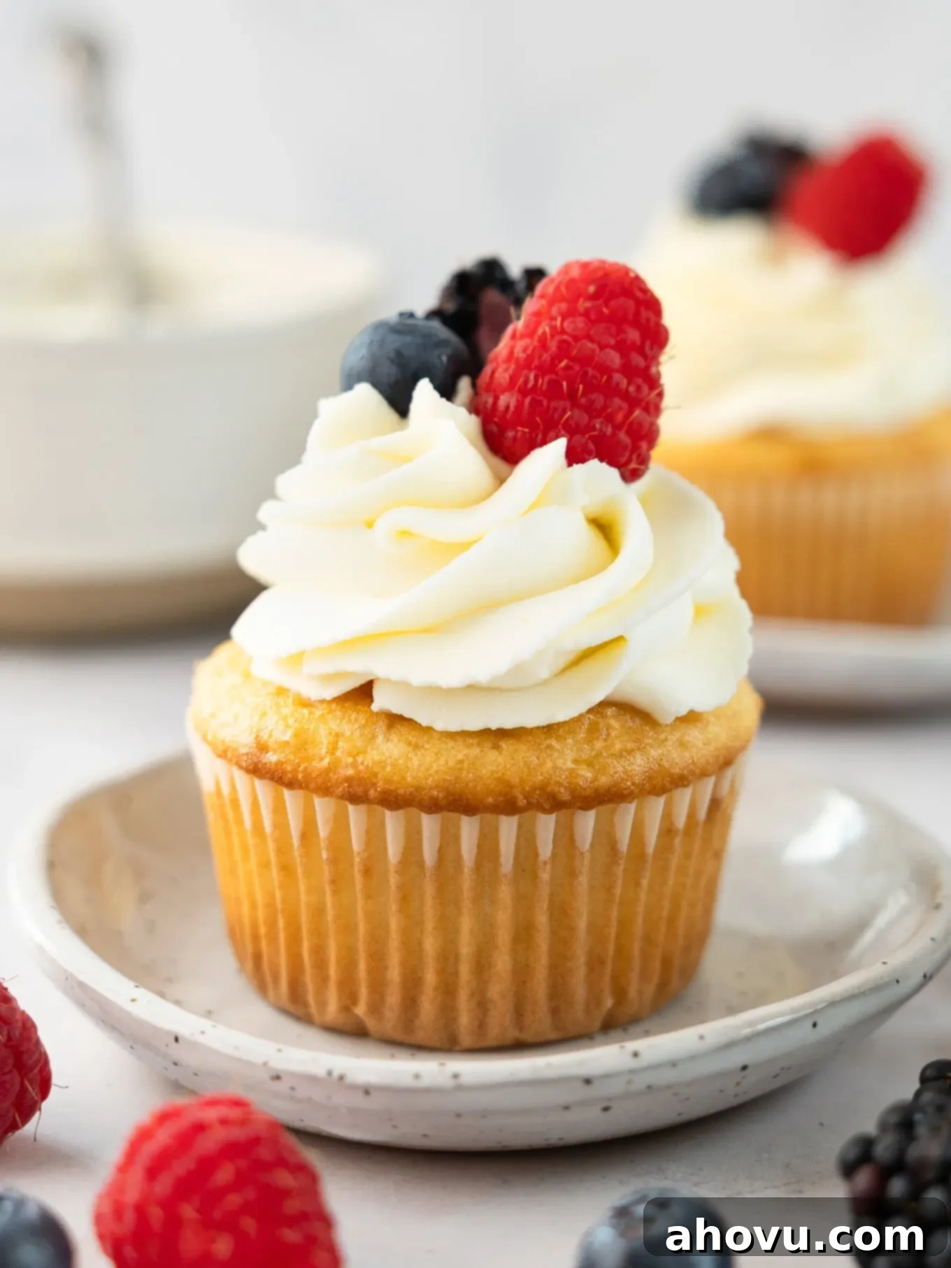 A vanilla cupcake topped with mascarpone frosting and fresh berries. 