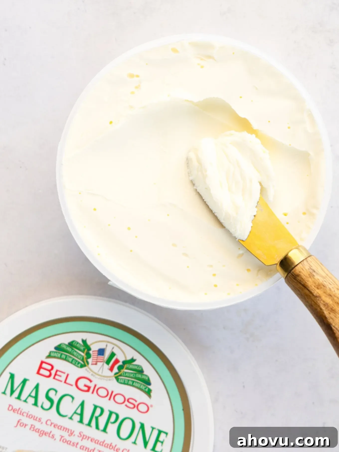 A container of mascarpone cheese with a knife in it.