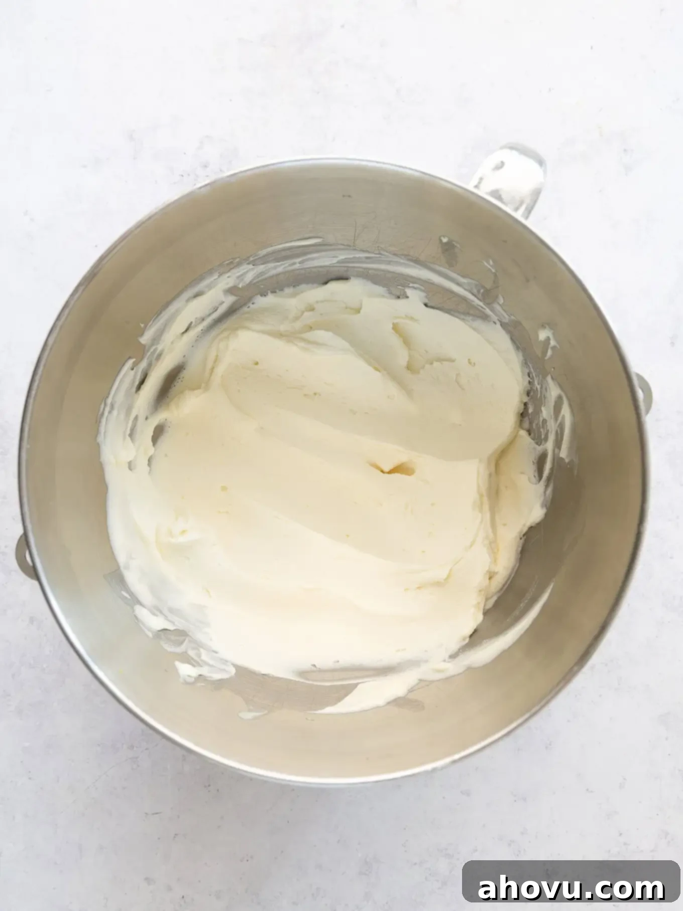 An overhead view of mascarpone frosting in the bowl of a stand mixer. 