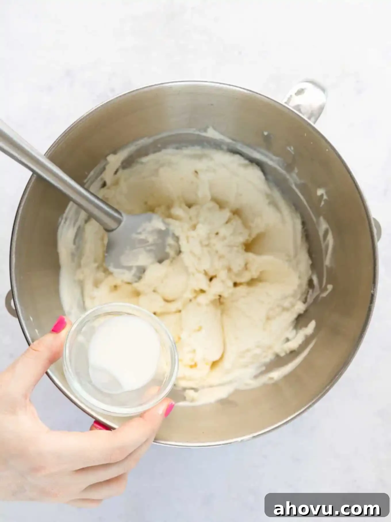 An overhead view of milk being added to curdled mascarpone frosting.