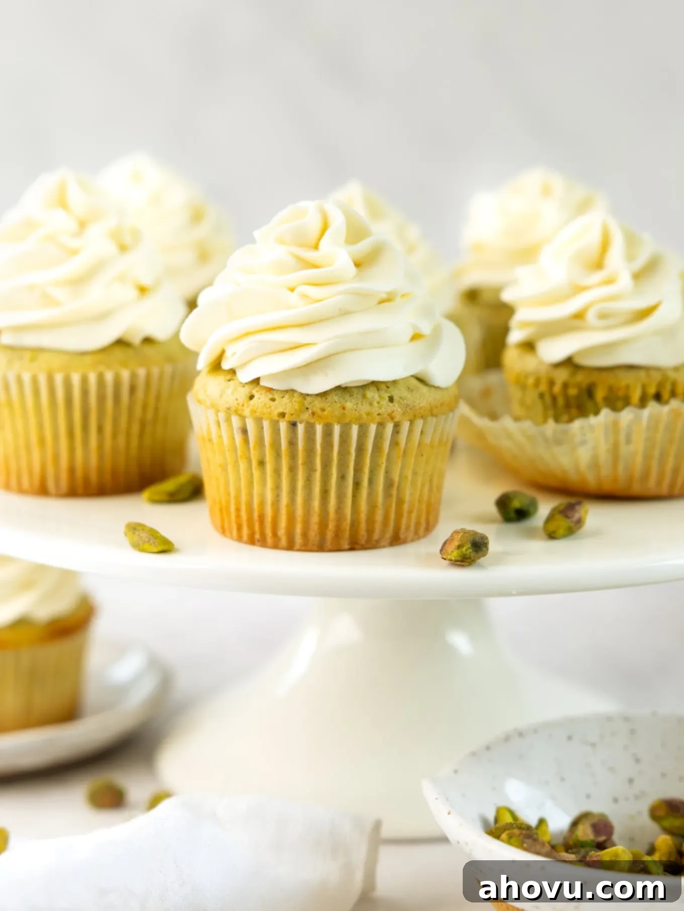 Pistachio cupcakes with mascarpone frosting on a cake stand. 