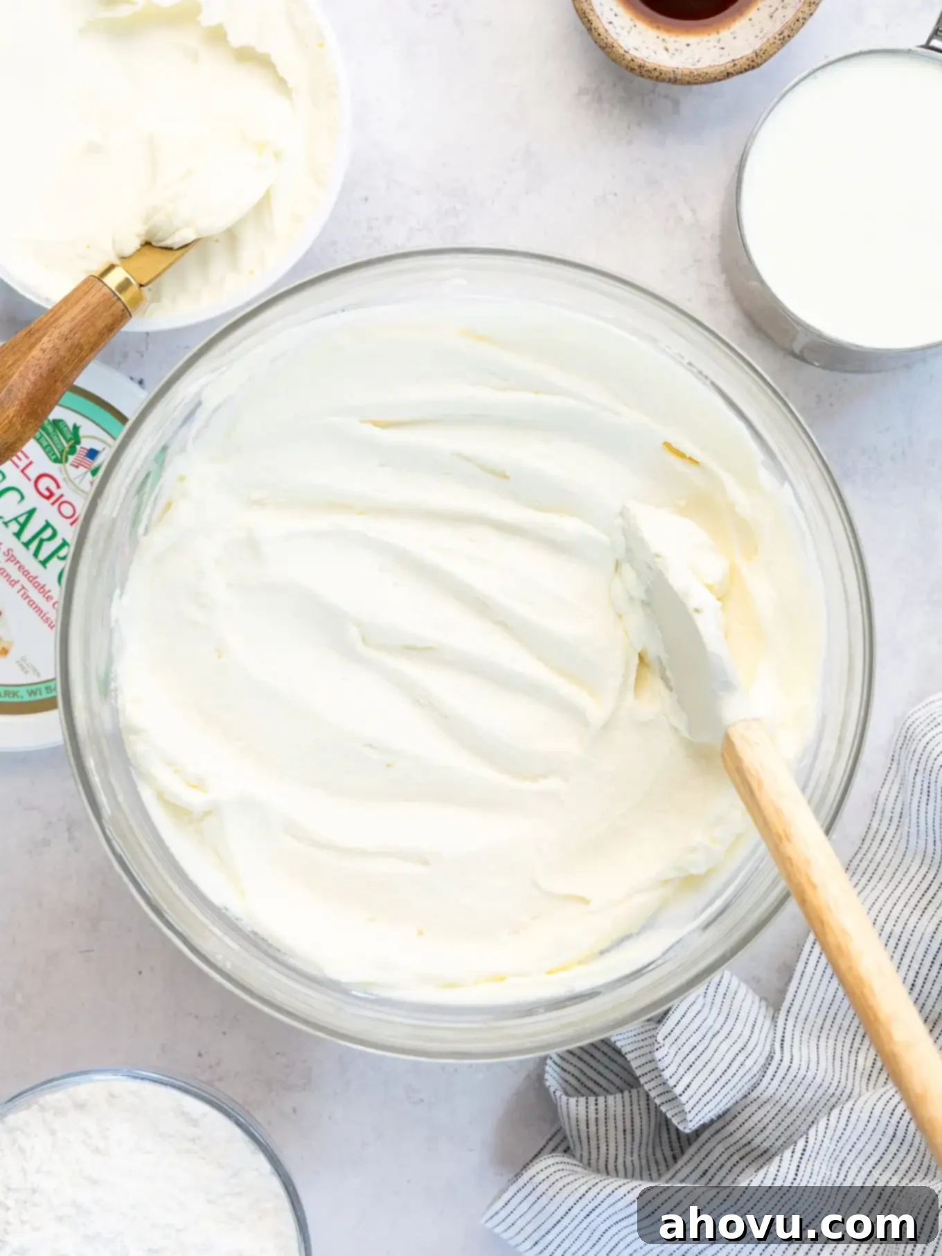 A bowl of mascarpone frosting with a rubber spatula in it.