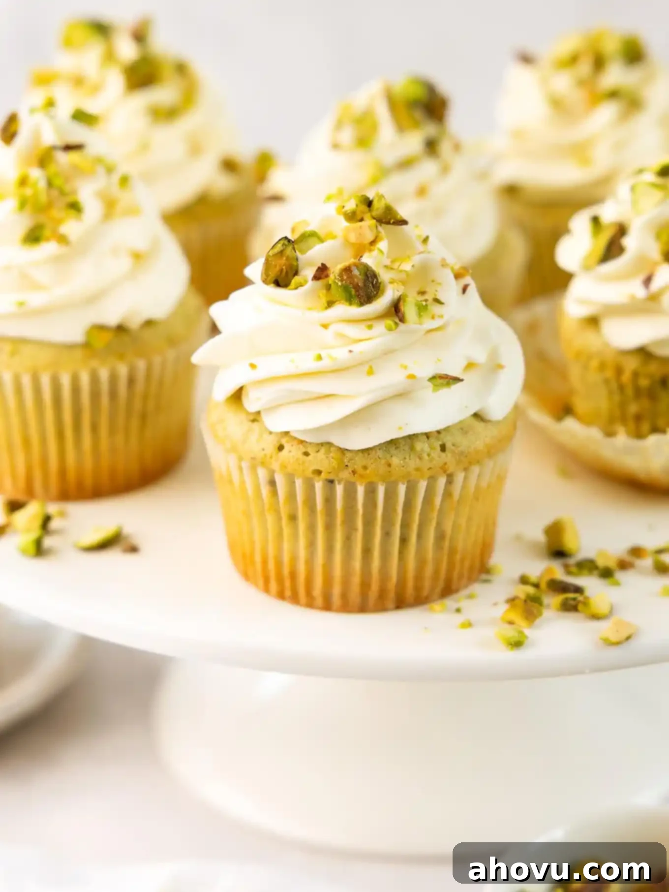 Frosted pistachio cupcakes on a cake stand, showcasing their delicate green hue and beautiful frosting swirls.