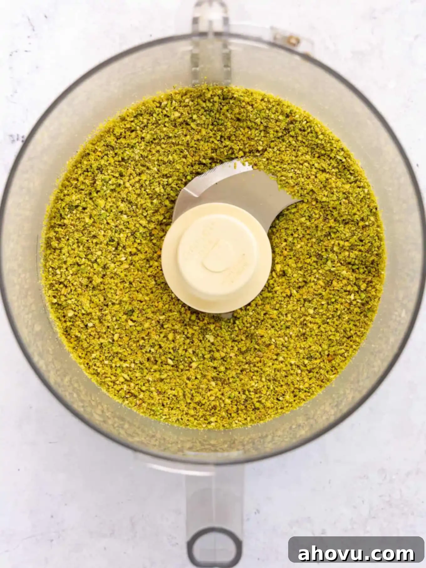 Ground pistachios in a food processor, showing a fine, crumbly texture.