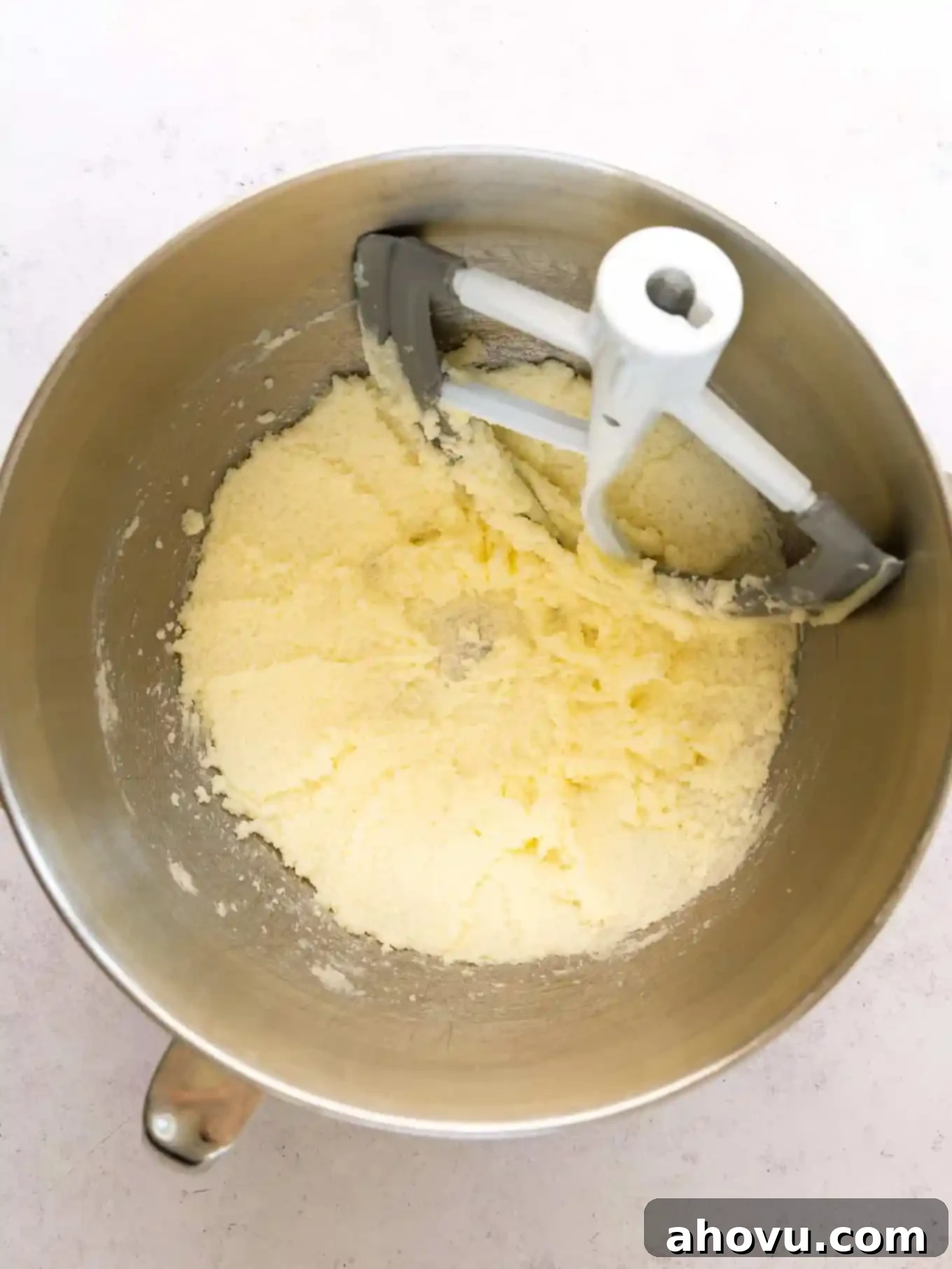Creamed butter and granulated sugar in a mixing bowl with a paddle attachment, showing a light and fluffy texture.