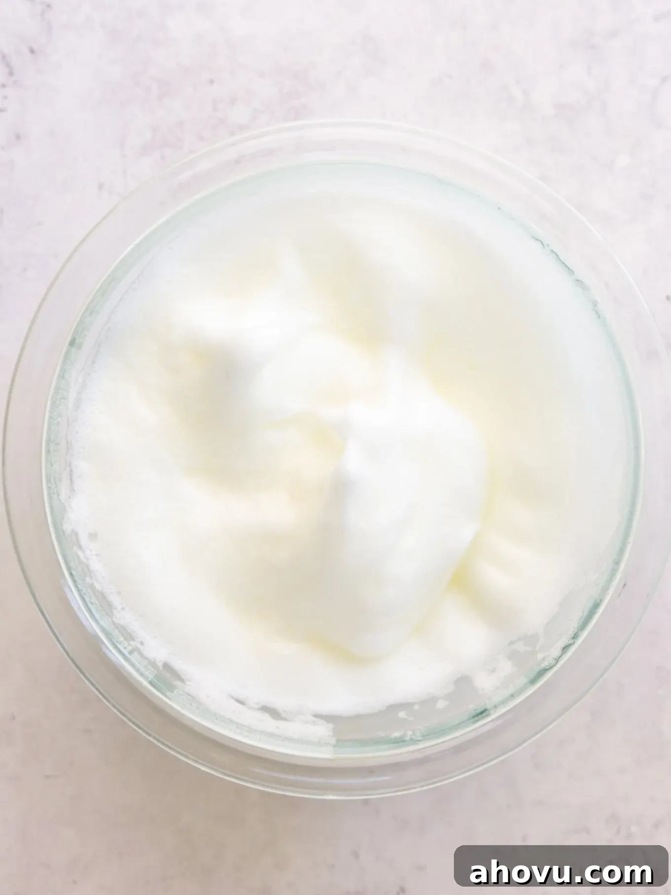 Whipped egg whites in a mixing bowl, showing stiff, standing peaks.