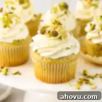 Several pistachio cupcakes on a white cake stand, artfully frosted.