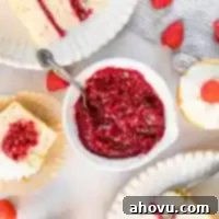 A bowl of glossy raspberry cake filling, surrounded by a frosted cake and filled cupcakes, showcasing its delicious application.