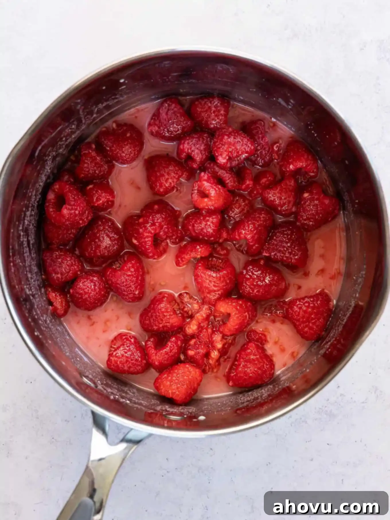 A saucepan filled with a vibrant mixture of raspberries, sugar, cornstarch, and lemon juice, prior to cooking.