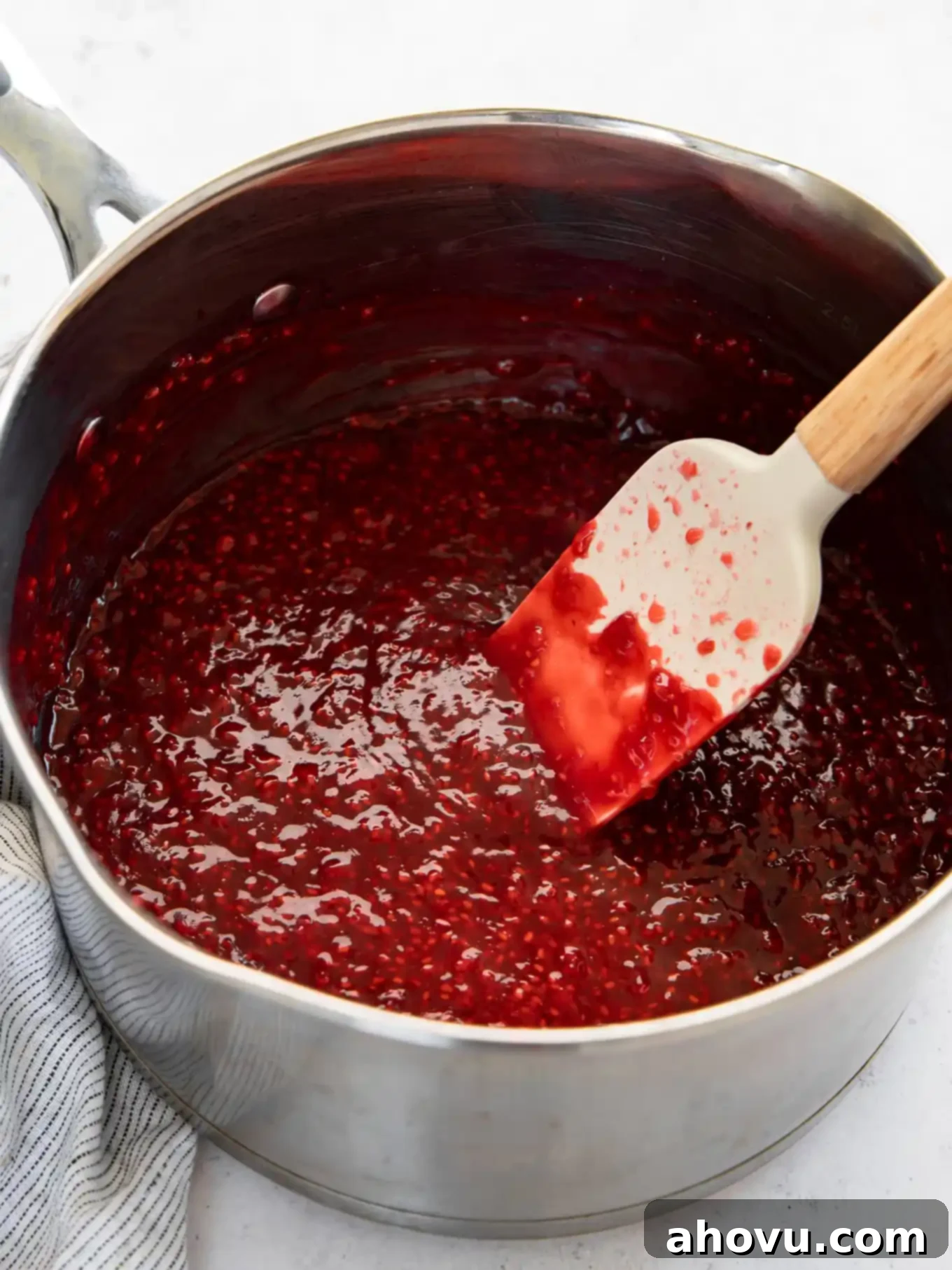 Thickened, glossy raspberry filling in a saucepan after being cooked on the stove, showing its smooth, rich texture.