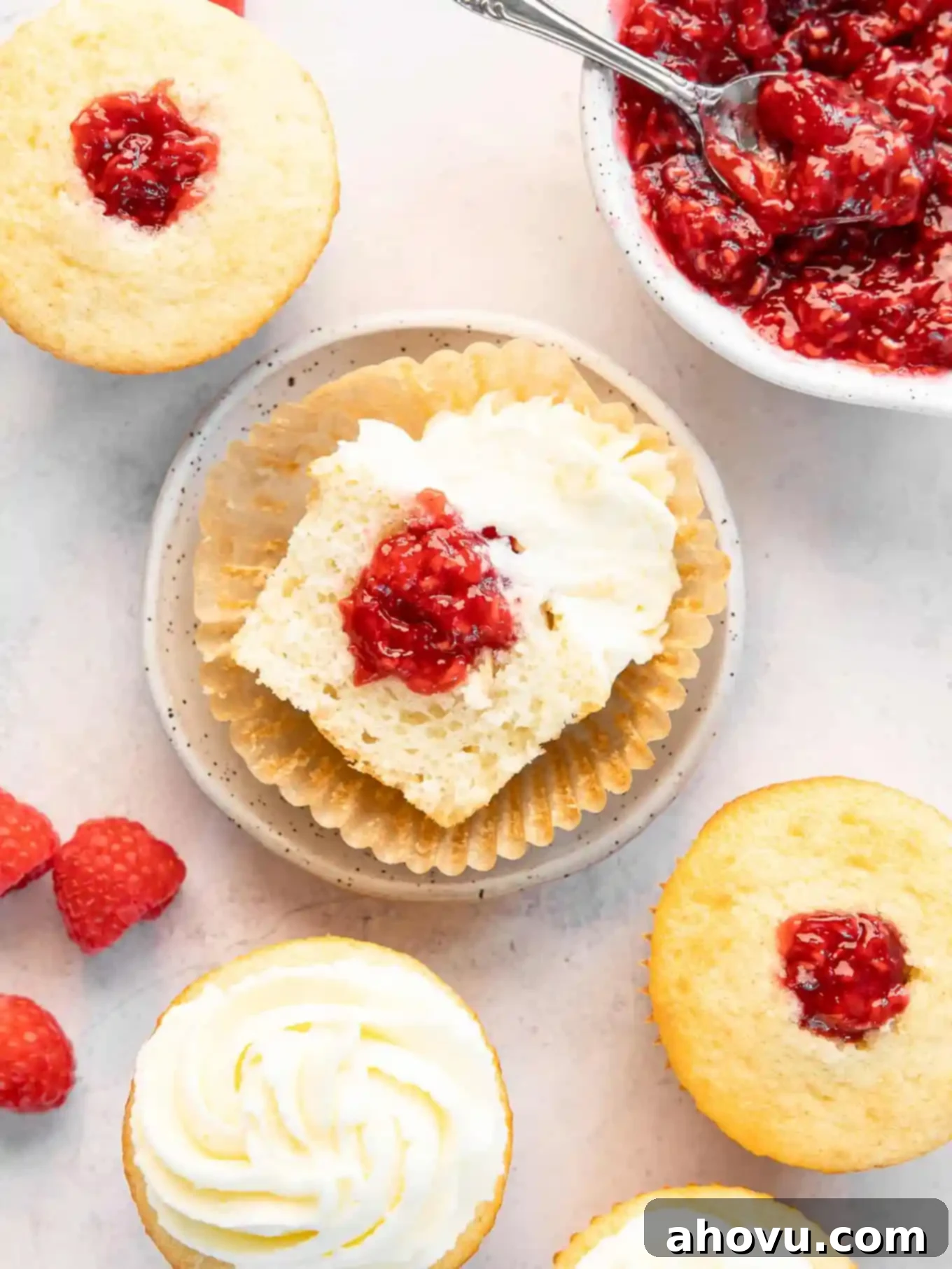 A delicious filled cupcake, turned on its side, revealing the generous layer of raspberry filling nestled within the tender crumb.