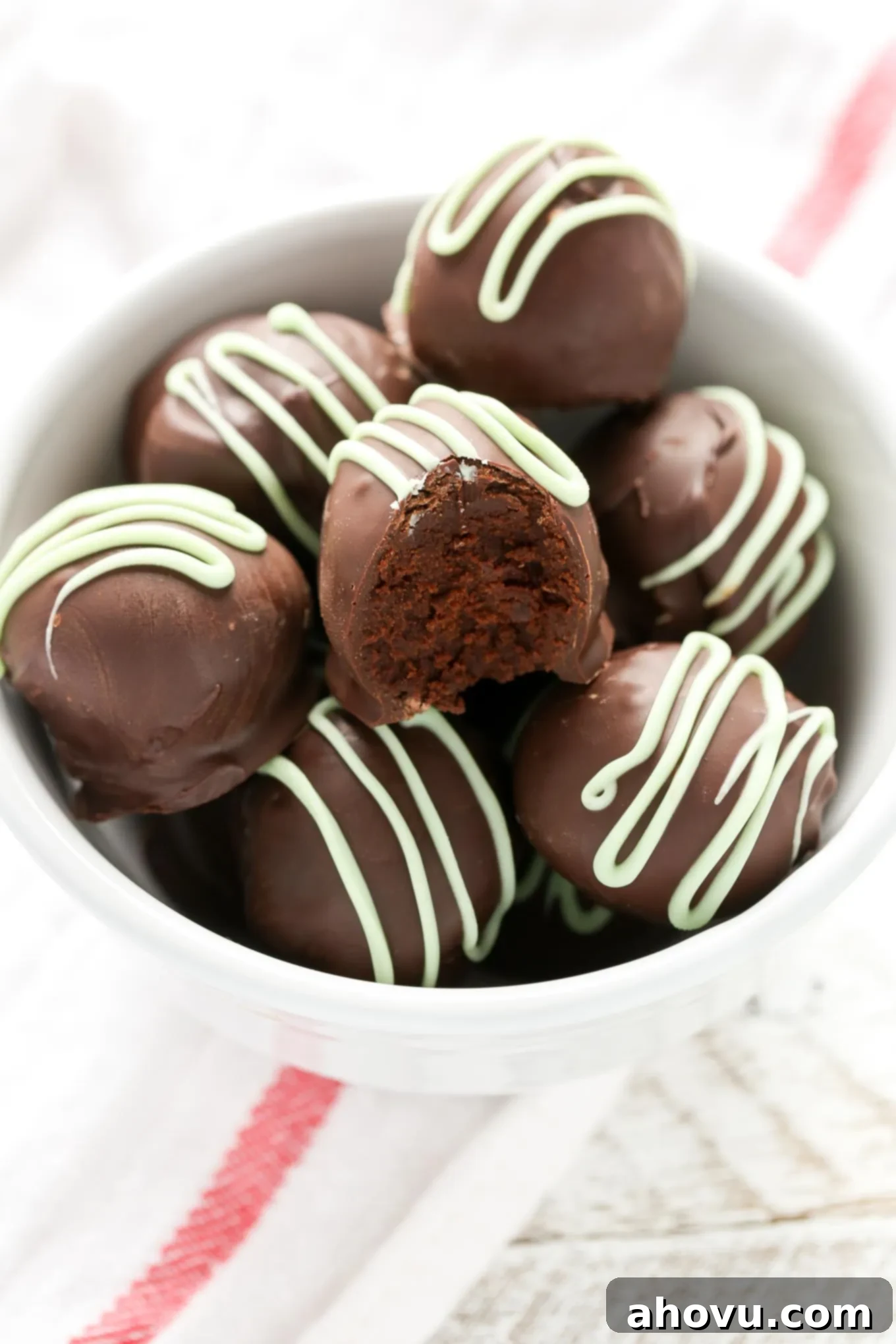 A bowl of rich mint chocolate ganache, perfectly smooth and glossy, with a spatula resting in it.