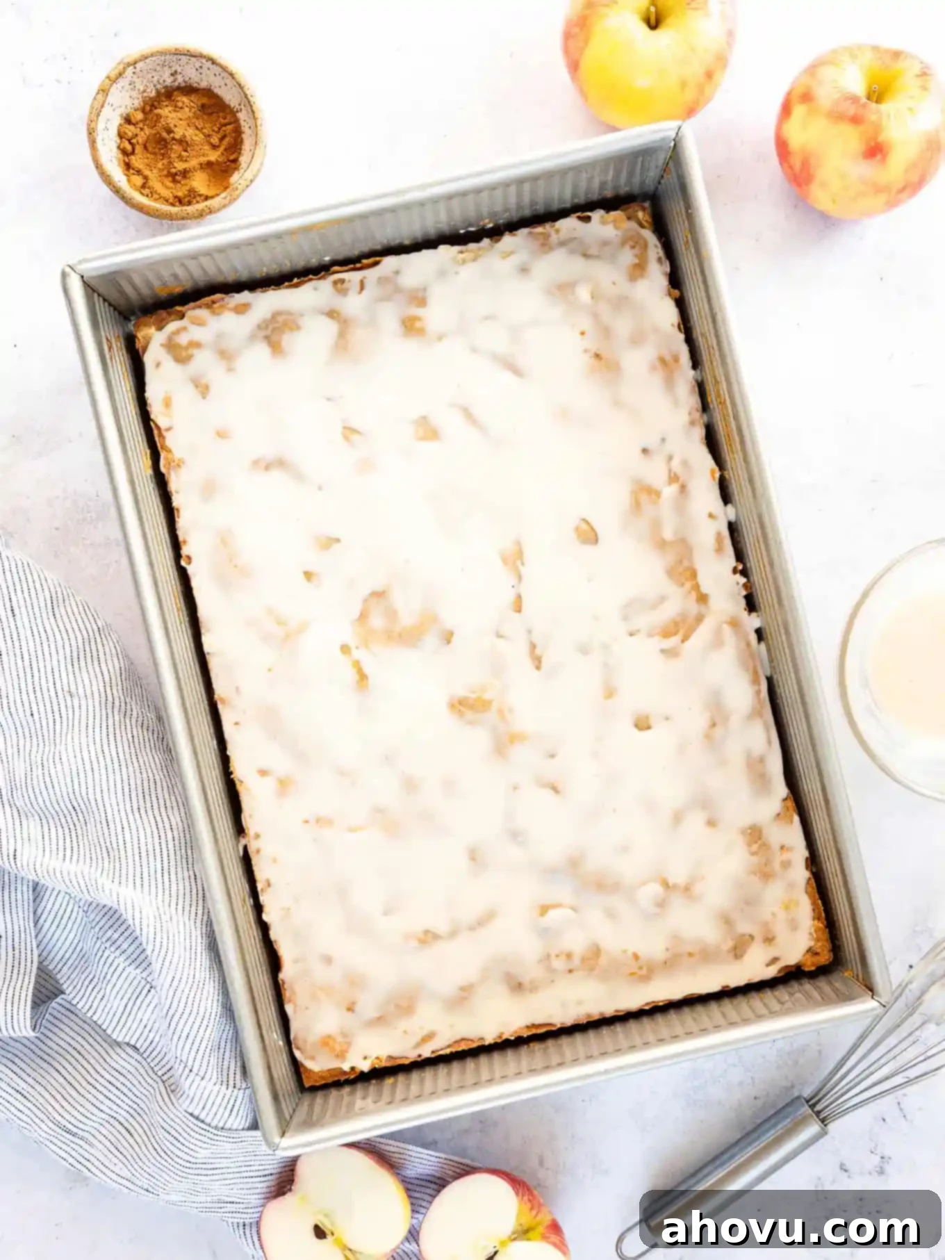 An apple fritter cake in a pan, after baking and being iced. 