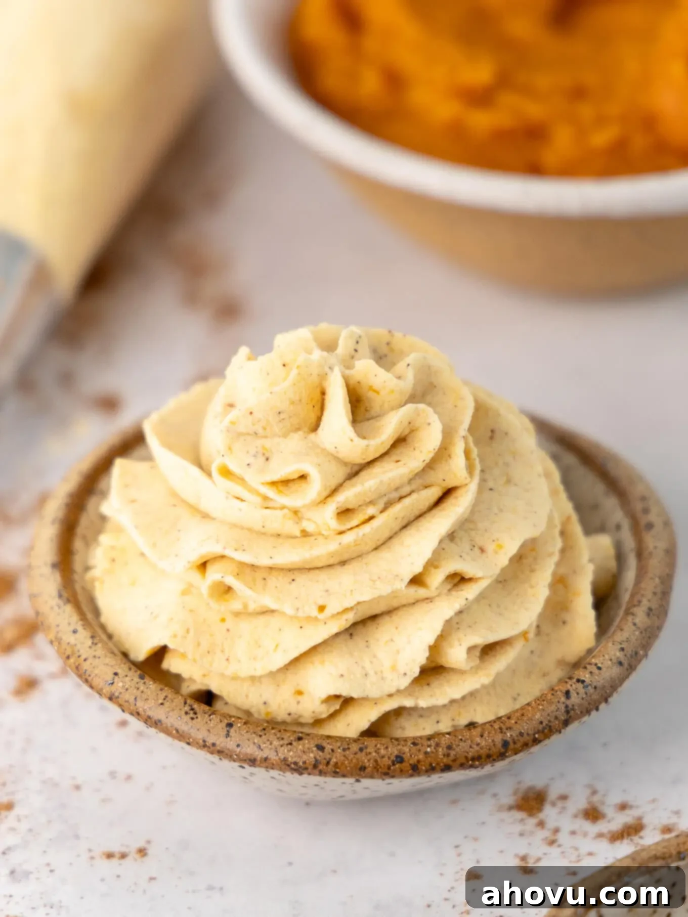A small bowl with pumpkin spice whipped cream piped into it, garnished with a sprinkle of extra spice, ready to be served.