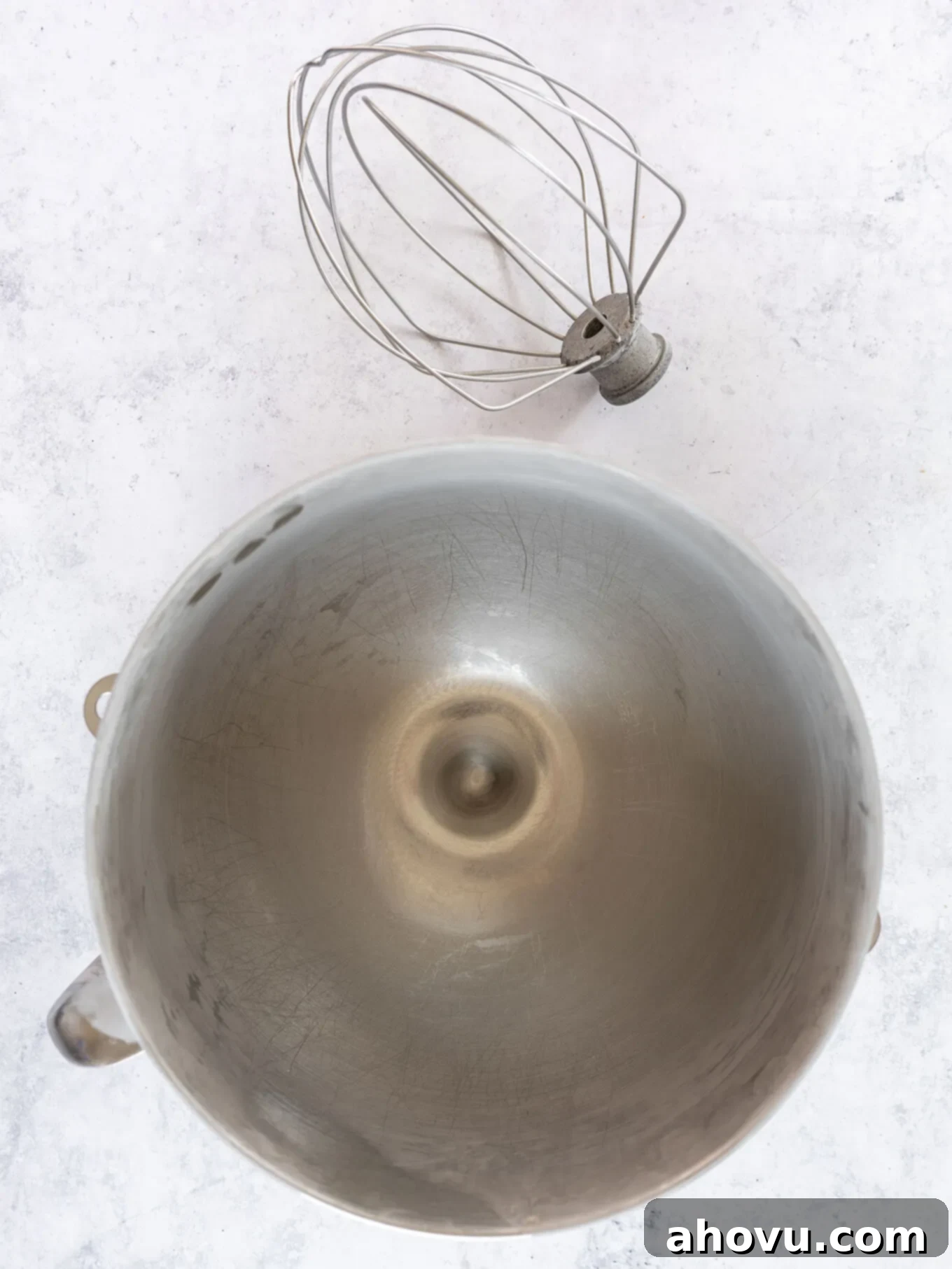 A chilled metal mixing bowl and whisk attachment, ready for whipping the cream.