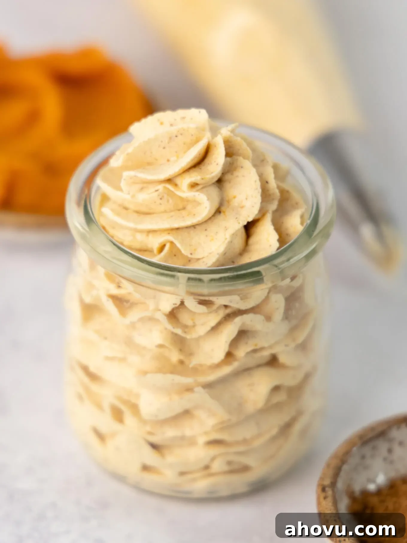 A charming glass jar filled with perfectly piped pumpkin spiced whipped cream, ready to be enjoyed as a delightful treat or topping.