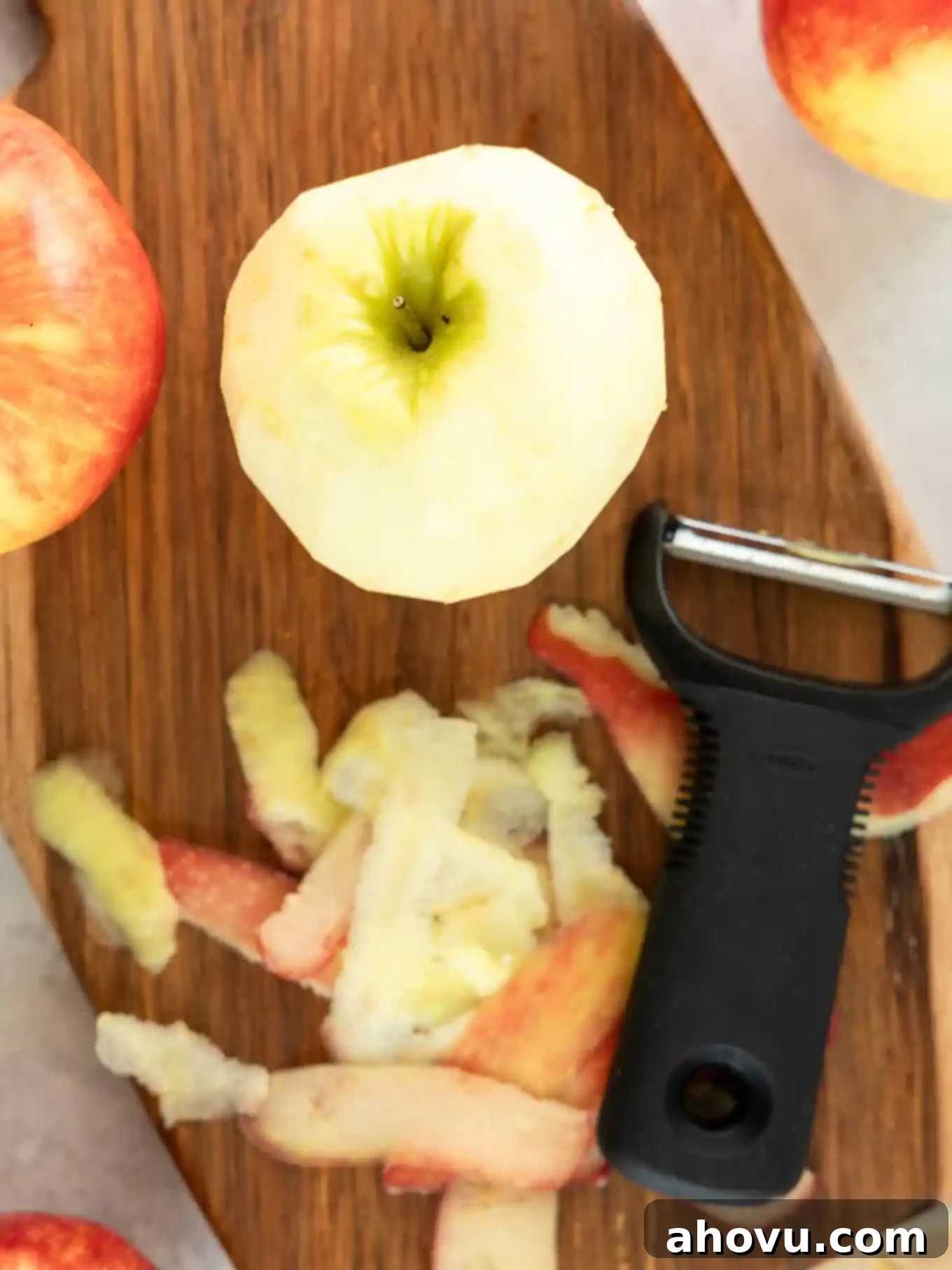 An apple being peeled on a cutting board. 