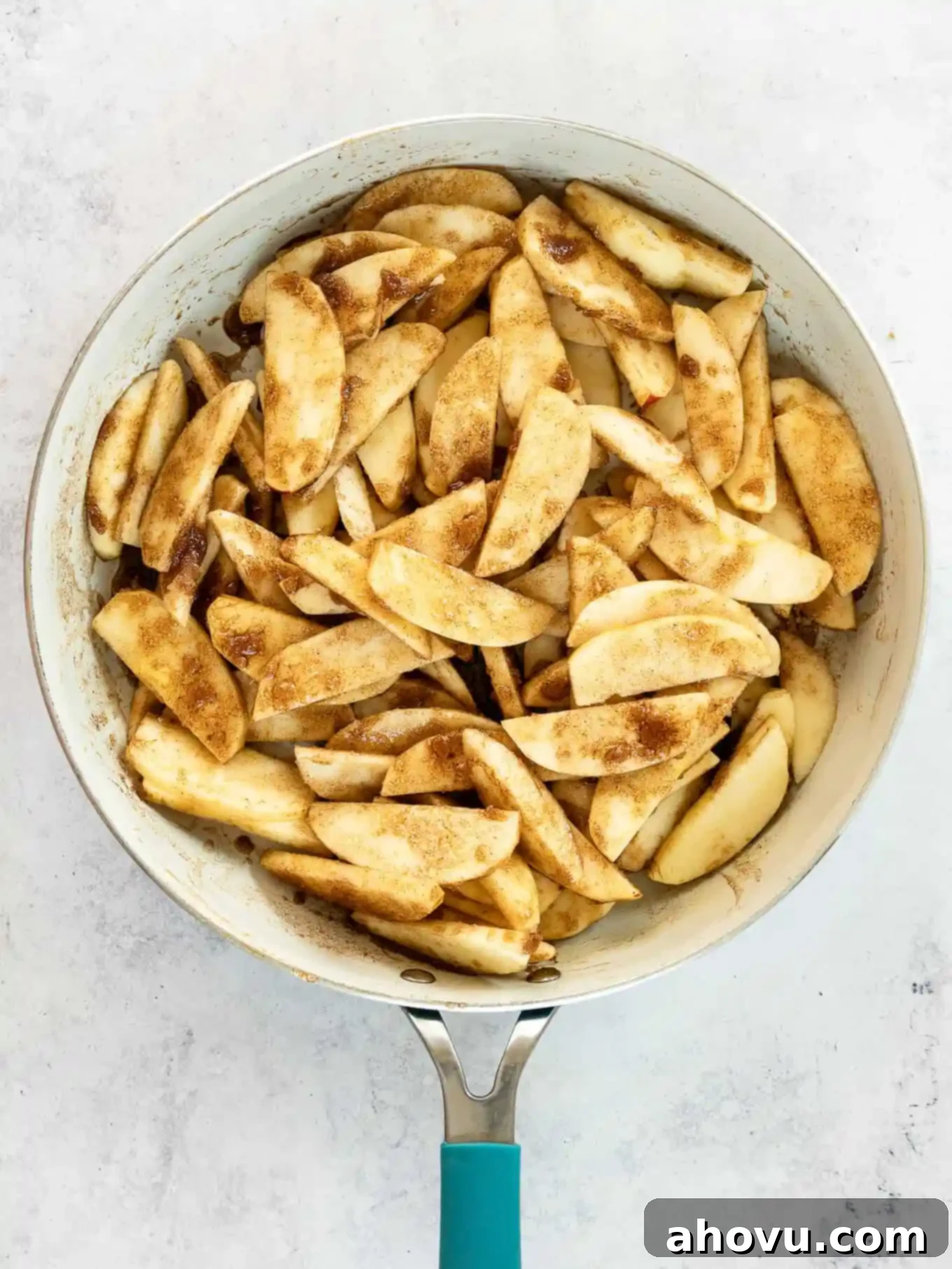 An overhead view of apples and spices in a skillet. 