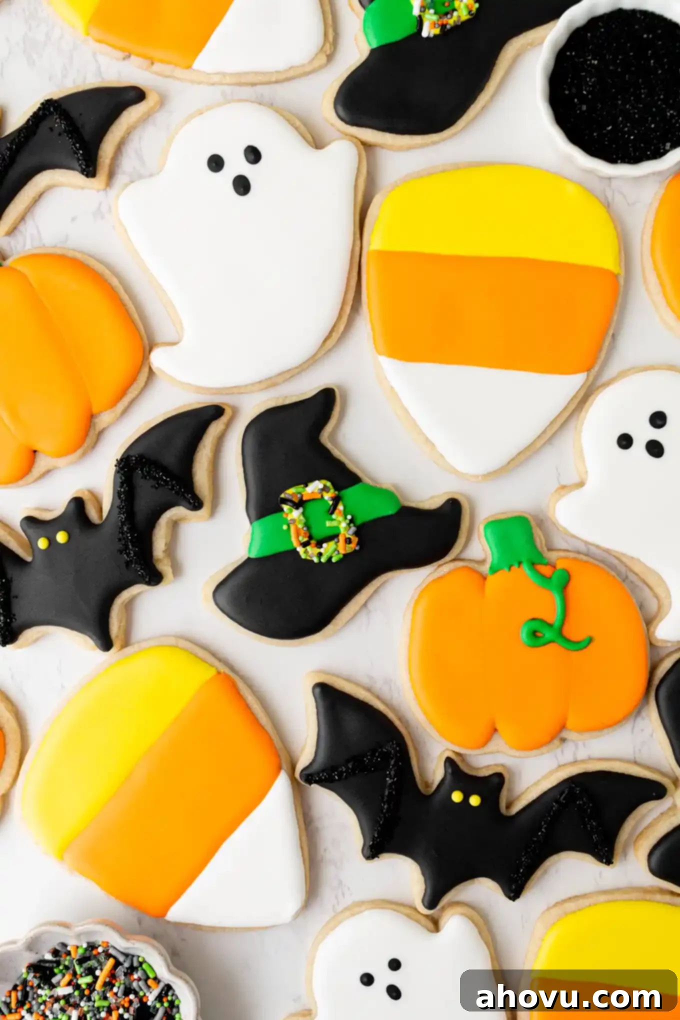 Frightfully Delicious Halloween Treats 2 An overhead view of an assortment of beautifully iced Halloween sugar cookies in various festive shapes like ghosts, bats, pumpkins, candy corn, and witches' hats.