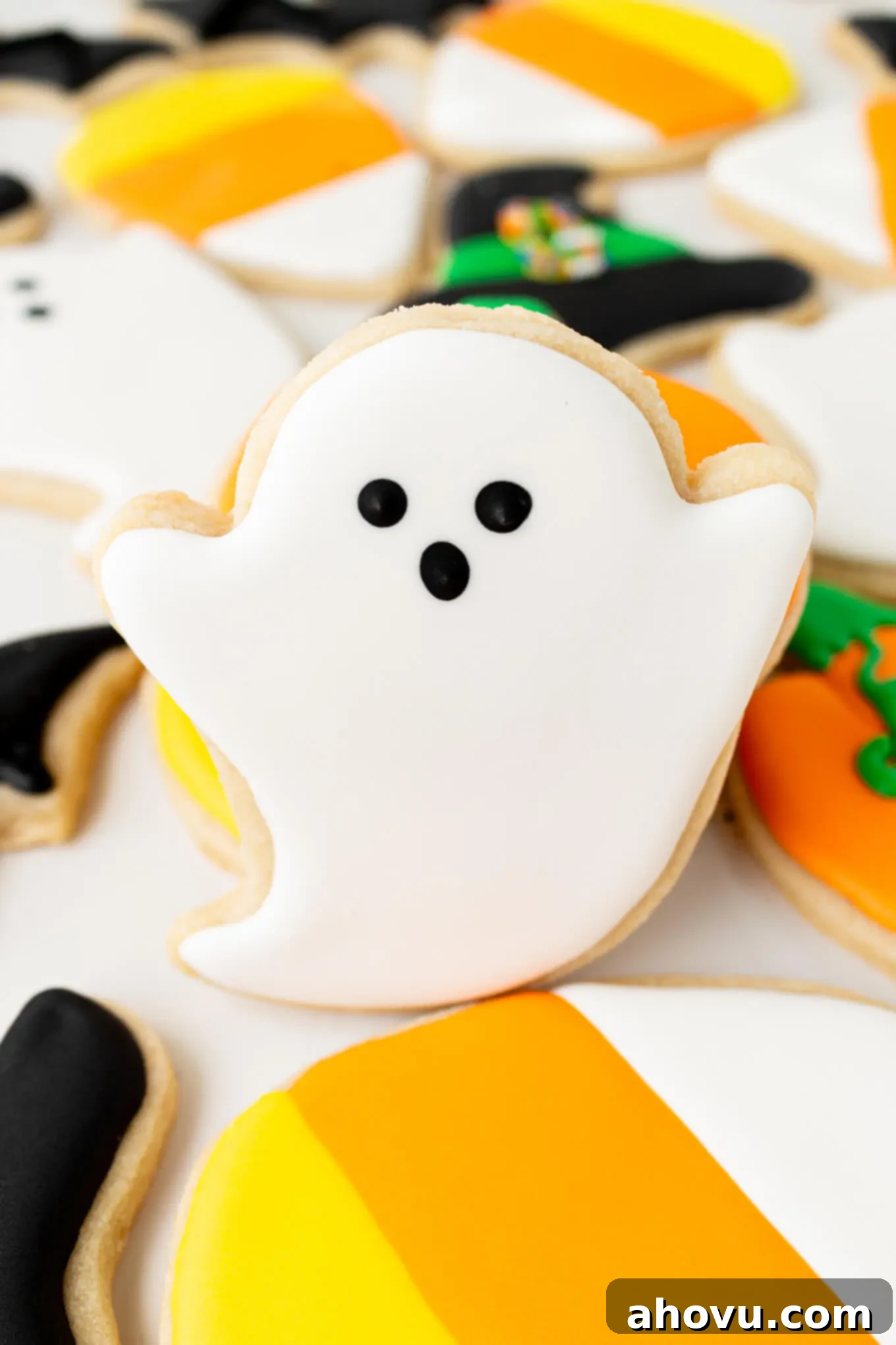 Frightfully Delicious Halloween Treats 11 A close-up of a charming ghost sugar cookie, perfectly outlined and flooded with white royal icing, featuring adorable black eyes and a mouth that blend smoothly into the wet base.
