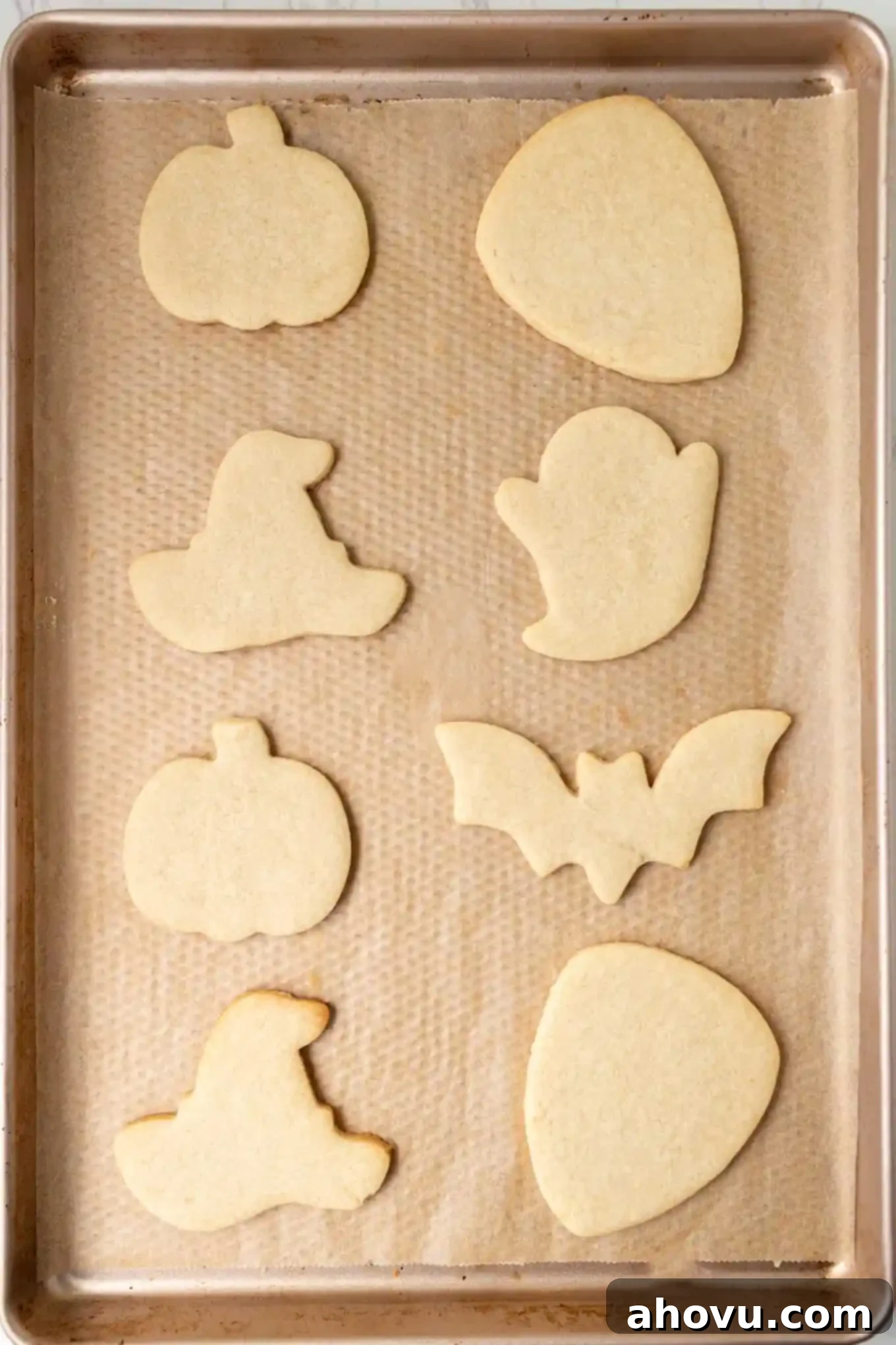 Frightfully Delicious Halloween Treats 5 An overhead view of freshly baked sugar cookies in different Halloween shapes, cooled and perfectly golden, awaiting their royal icing decoration.