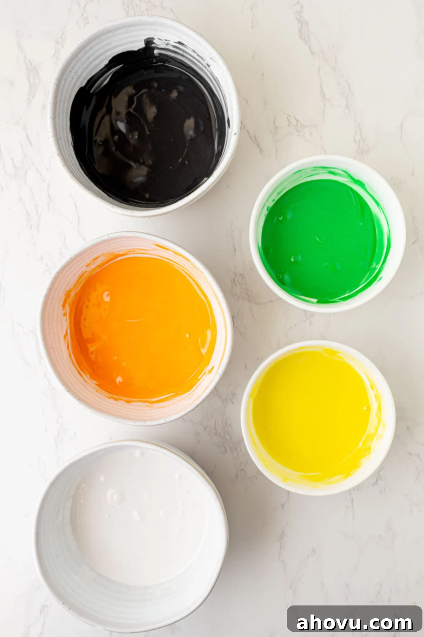 Frightfully Delicious Halloween Treats 6 Five separate ramekins filled with different colors of vibrant royal icing, ready for piping.