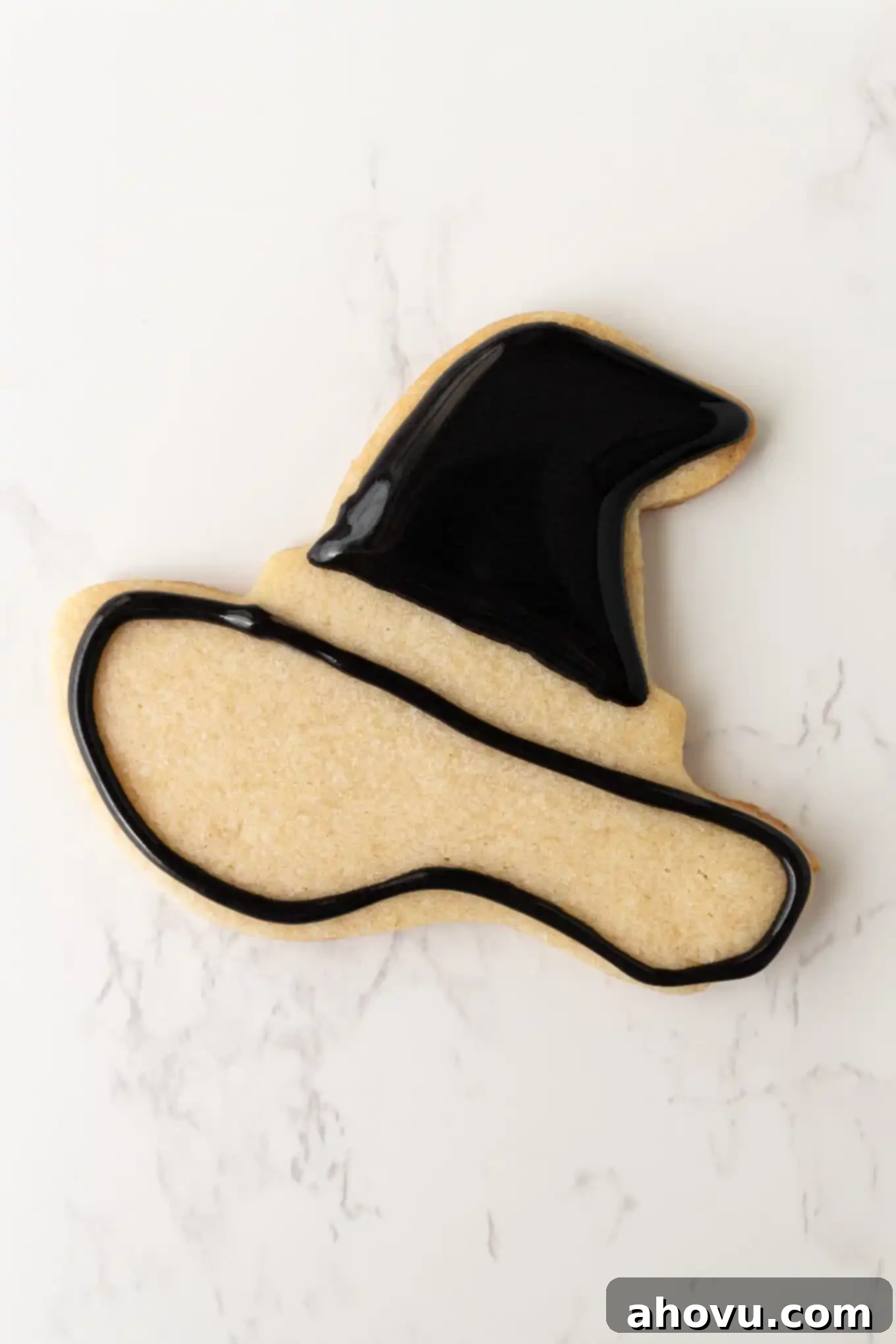 Frightfully Delicious Halloween Treats 8 A witch's hat sugar cookie demonstrating the two-stage decorating process: one part is neatly outlined and flooded, while the other part is only outlined, showing the precision possible with royal icing.