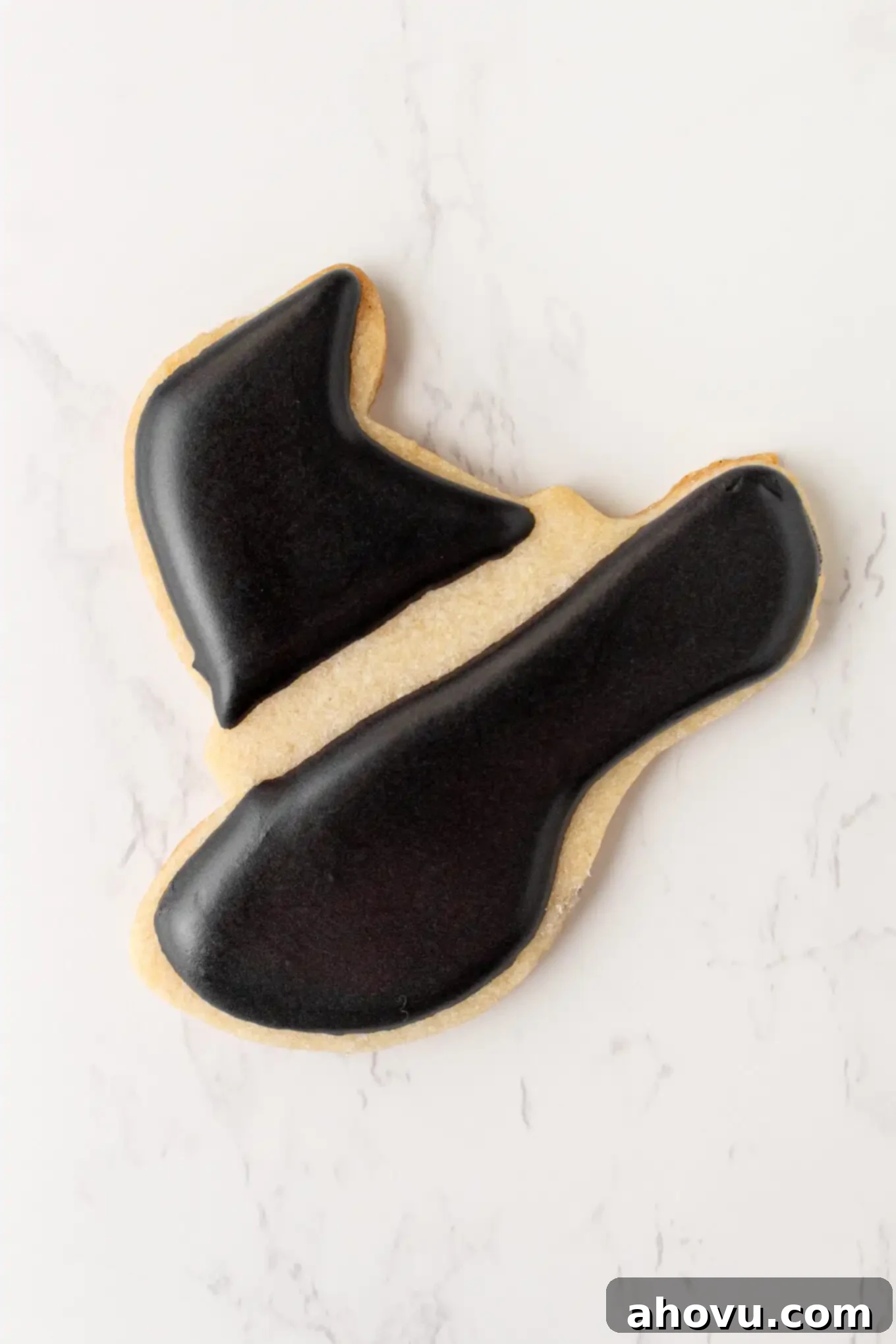 Frightfully Delicious Halloween Treats 9 A witch's hat sugar cookie mid-decoration, showing a clear separation between the black hat base and the green band, highlighting the crisp lines achievable with royal icing.