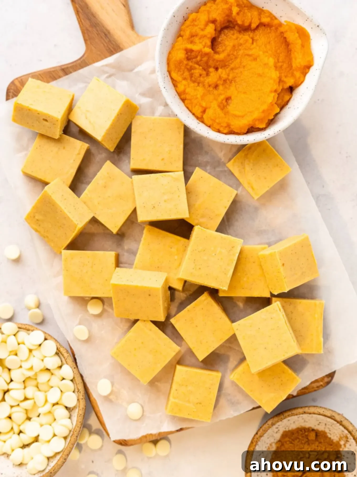 Pumpkin Spice Fudge 2 An overhead view of rich, orange pumpkin fudge squares, alongside pumpkin puree and white chocolate chips, highlighting the key ingredients.