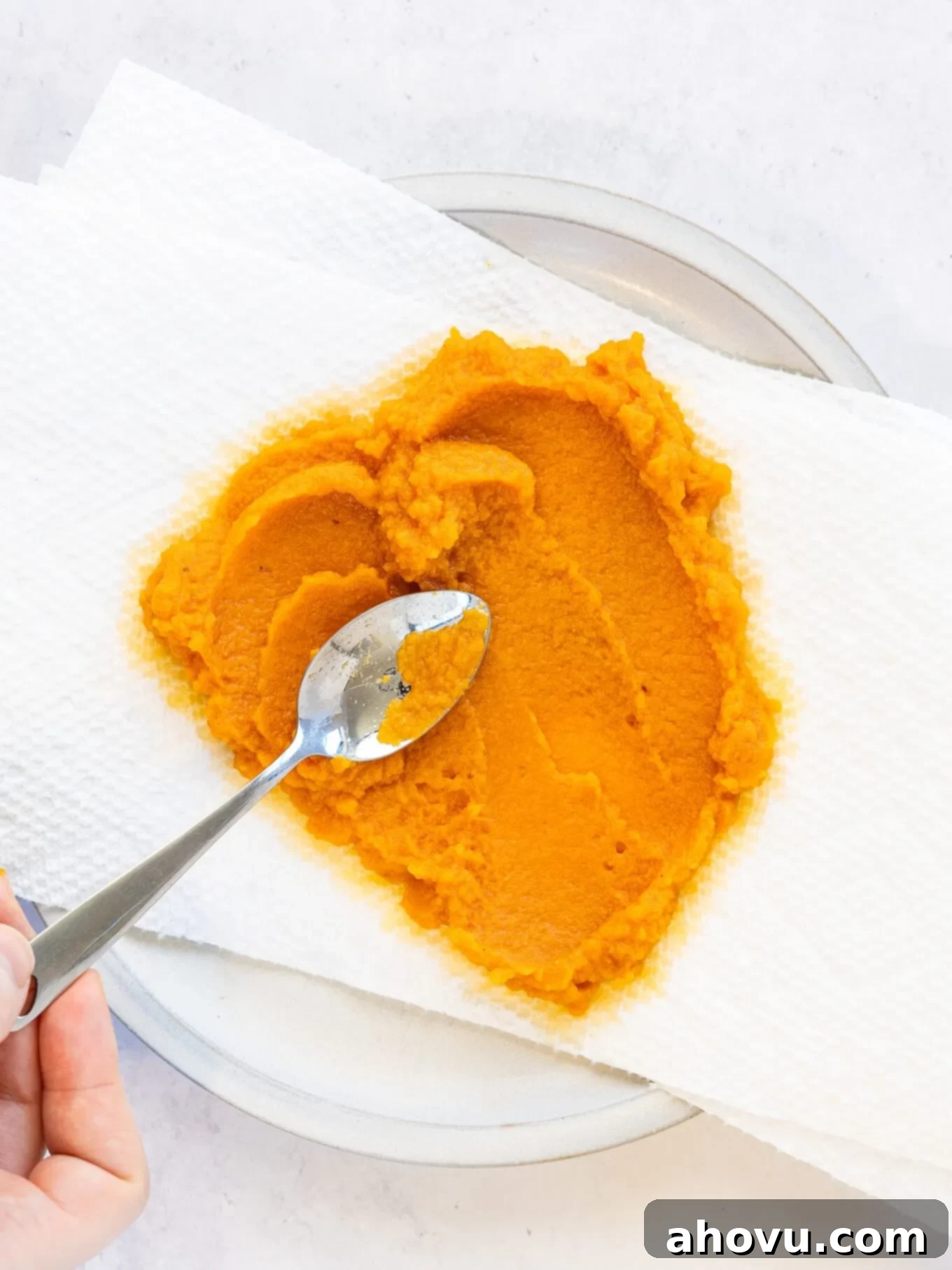Pumpkin Spice Fudge 4 An overhead view of pumpkin puree being spread evenly over layers of paper towels to absorb excess moisture.