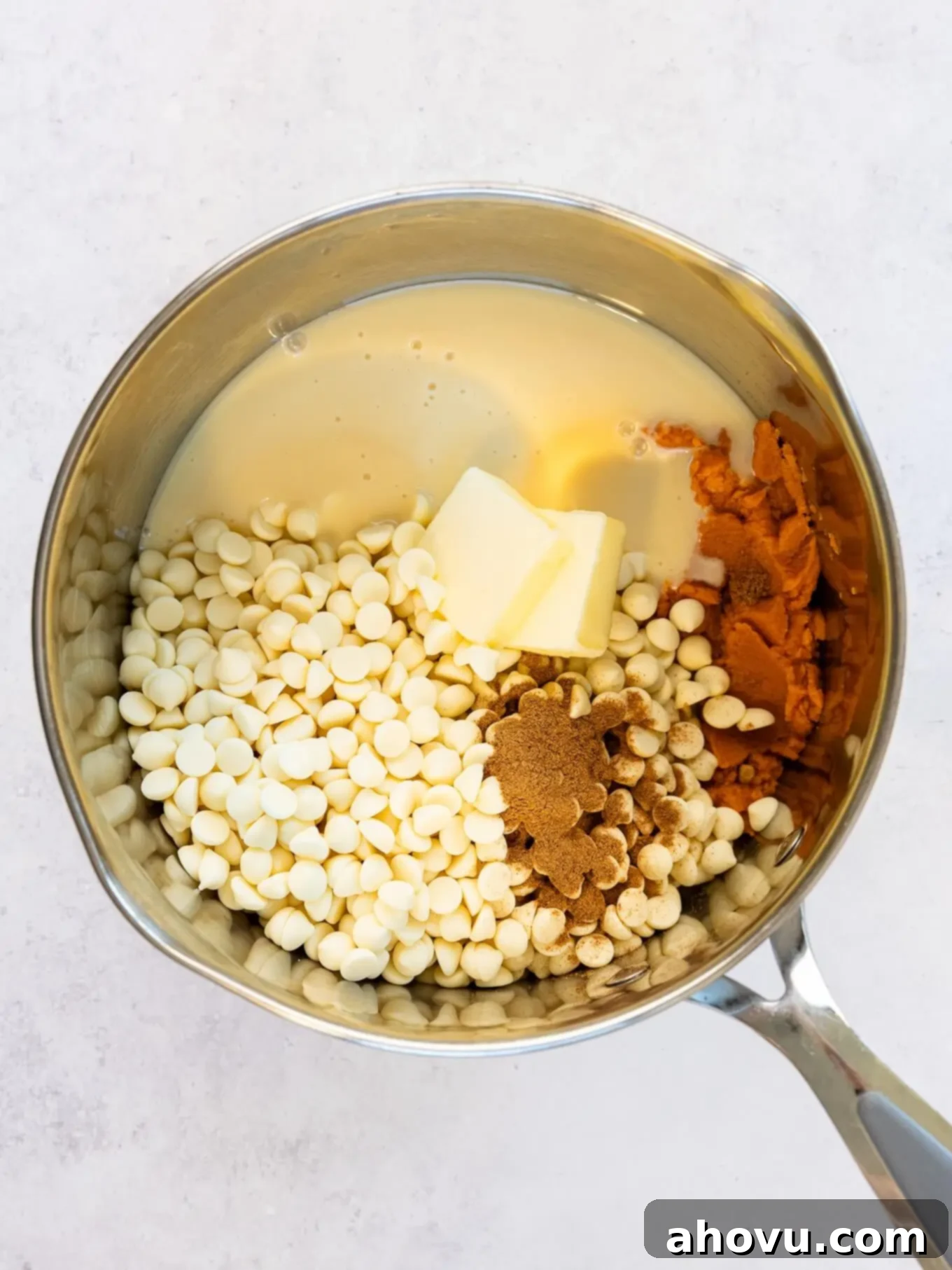 Pumpkin Spice Fudge 6 An overhead view of all the pumpkin fudge ingredients, including blotted pumpkin puree, white chocolate chips, and sweetened condensed milk, combined in a saucepan ready for melting.