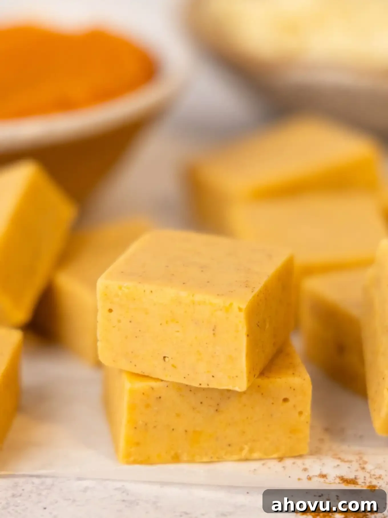 Pumpkin Spice Fudge 8 Several neatly cut squares of rich pumpkin fudge arranged artfully on a white surface.