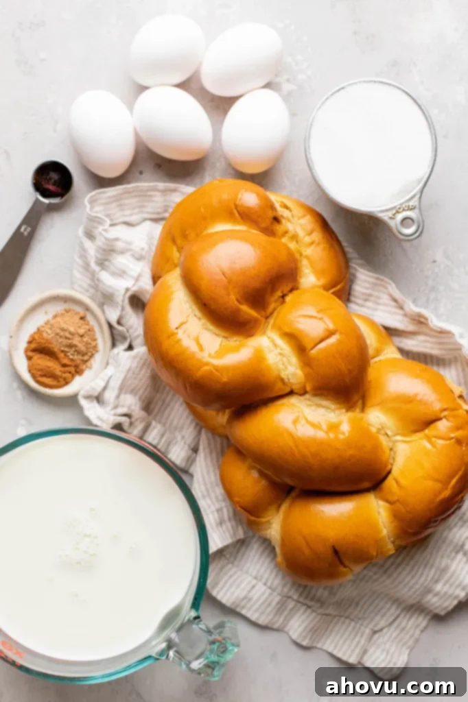 The simple, fresh ingredients needed to make homemade bread pudding, laid out on a clean gray surface, including eggs, milk, sugar, bread, and spices.