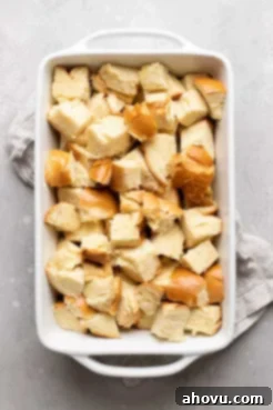 A white 9x13 baking pan filled with evenly cubed day-old bread, ready for the custard.