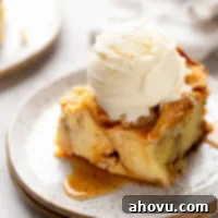 A slice of bread pudding with a scoop of ice cream on top on a white speckled plate, highlighting its delicious appeal.