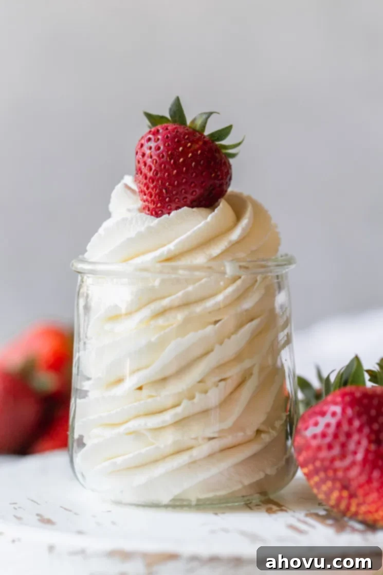 Artisan Whipped Cream 2 A small glass jar filled with homemade whipped cream topped with a strawberry.