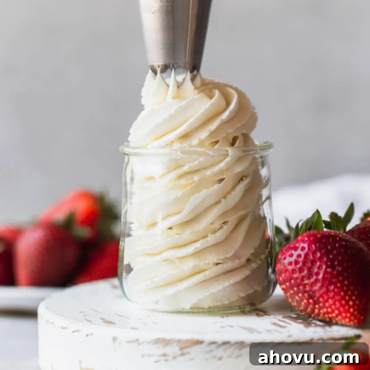 Artisan Whipped Cream 6 Homemade whipped cream being piped into a small glass jar surrounded by strawberries.