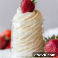 Artisan Whipped Cream 7 A small glass jar filled with whipped cream and topped with a strawberry.