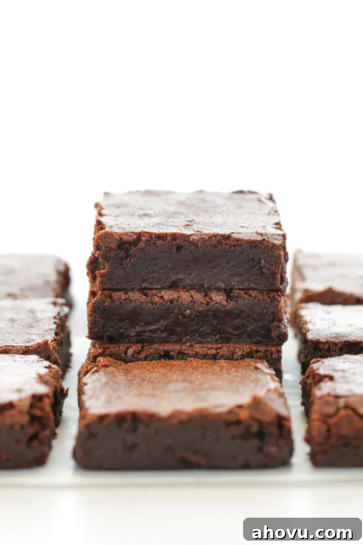Heavenly Homemade Brownies 2 A delectable stack of perfectly sliced fudgy brownies on parchment paper, surrounded by more rich chocolate brownies.