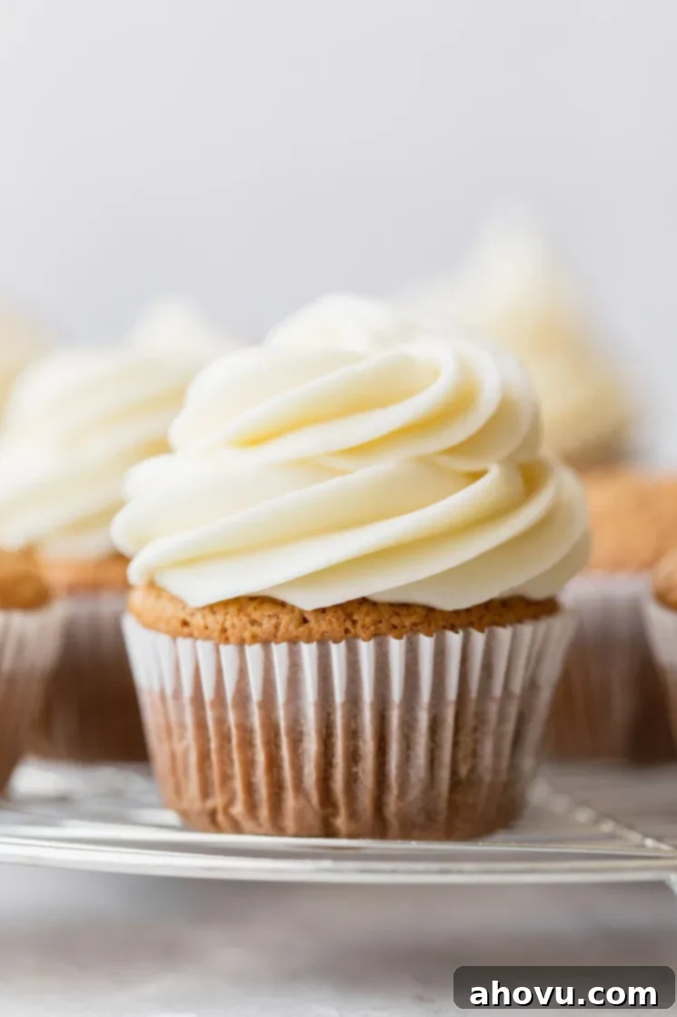 Velvet Cream Cloud 2 A group of cupcakes resting on a round cooling rack topped with cream cheese frosting.