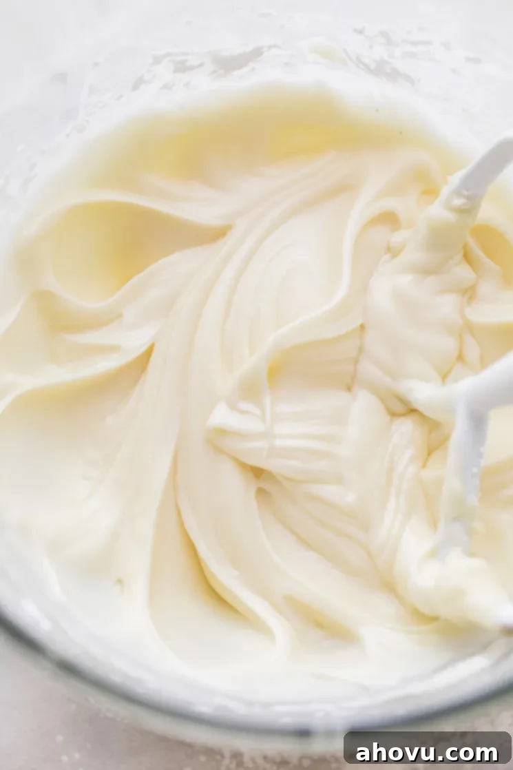 Velvet Cream Cloud 4 A glass mixing bowl with cream cheese frosting and the beater that was used to mix it up.