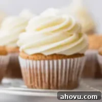 Velvet Cream Cloud 6 A cupcake topped with cream cheese frosting on a round cooling rack.