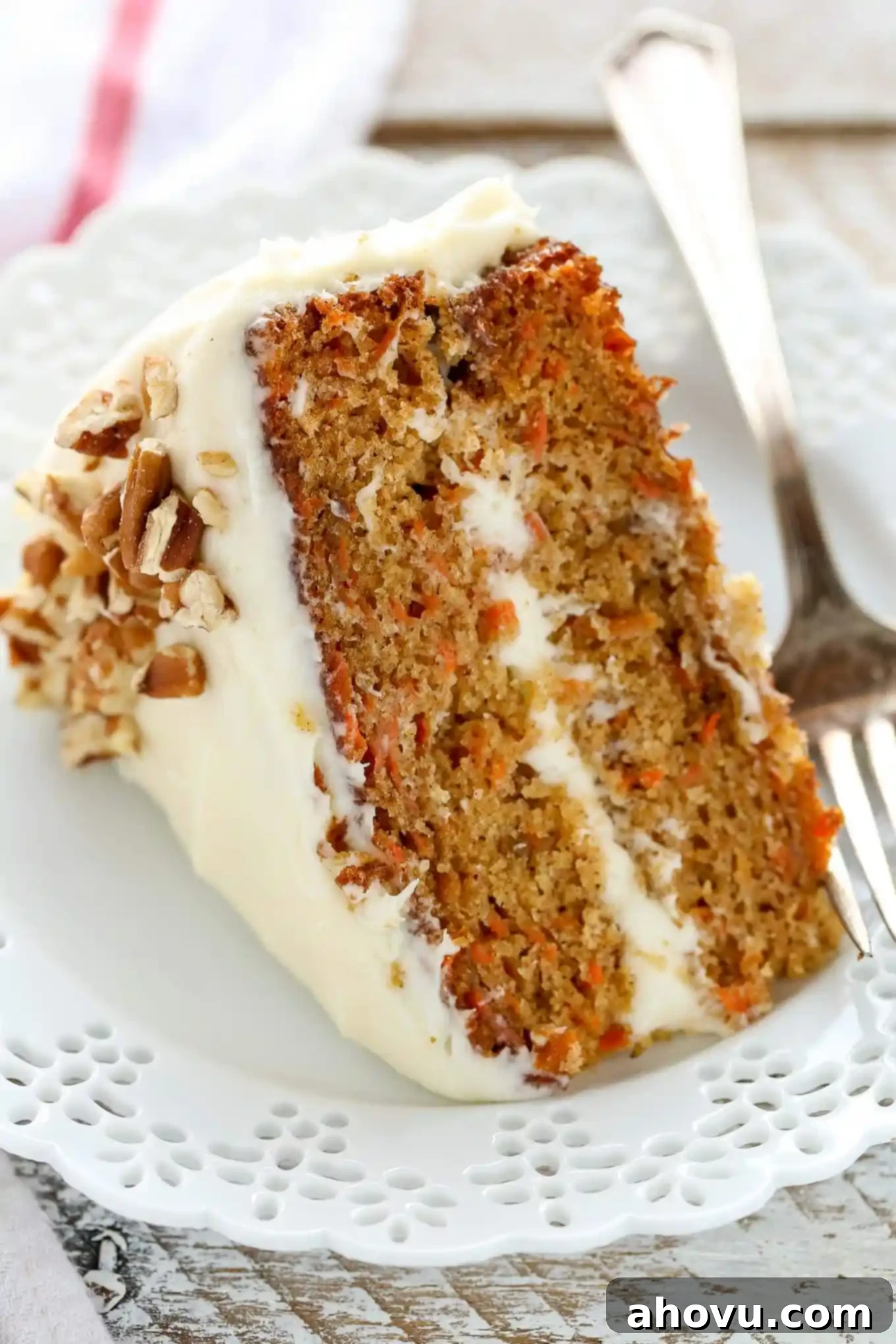 Irresistible Carrot Cake Delight 15 A close-up, mouth-watering view of a single slice of carrot cake, elegantly presented on a decorative white plate, highlighting its moist layers and creamy frosting.