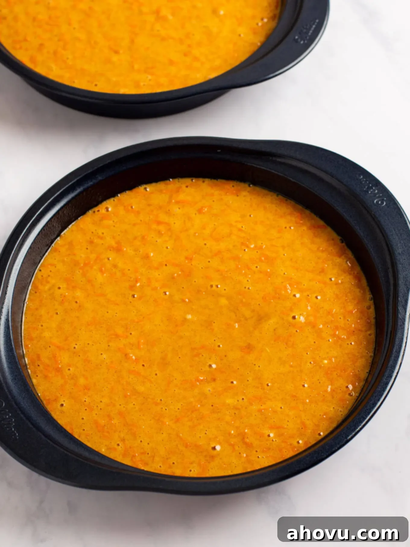 Irresistible Carrot Cake Delight 8 Smooth carrot cake batter being carefully poured and divided evenly into two prepared 9-inch round cake pans, ready for the oven.