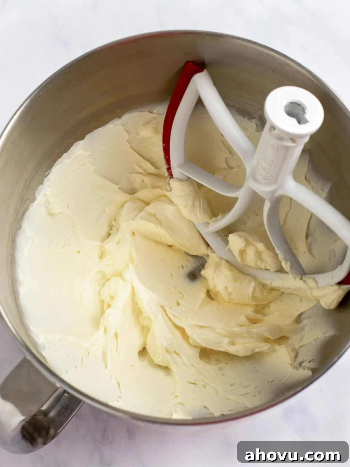 Irresistible Carrot Cake Delight 9 Cream cheese and softened butter being beaten together in the bowl of a stand mixer, creating a smooth and creamy base for the frosting.