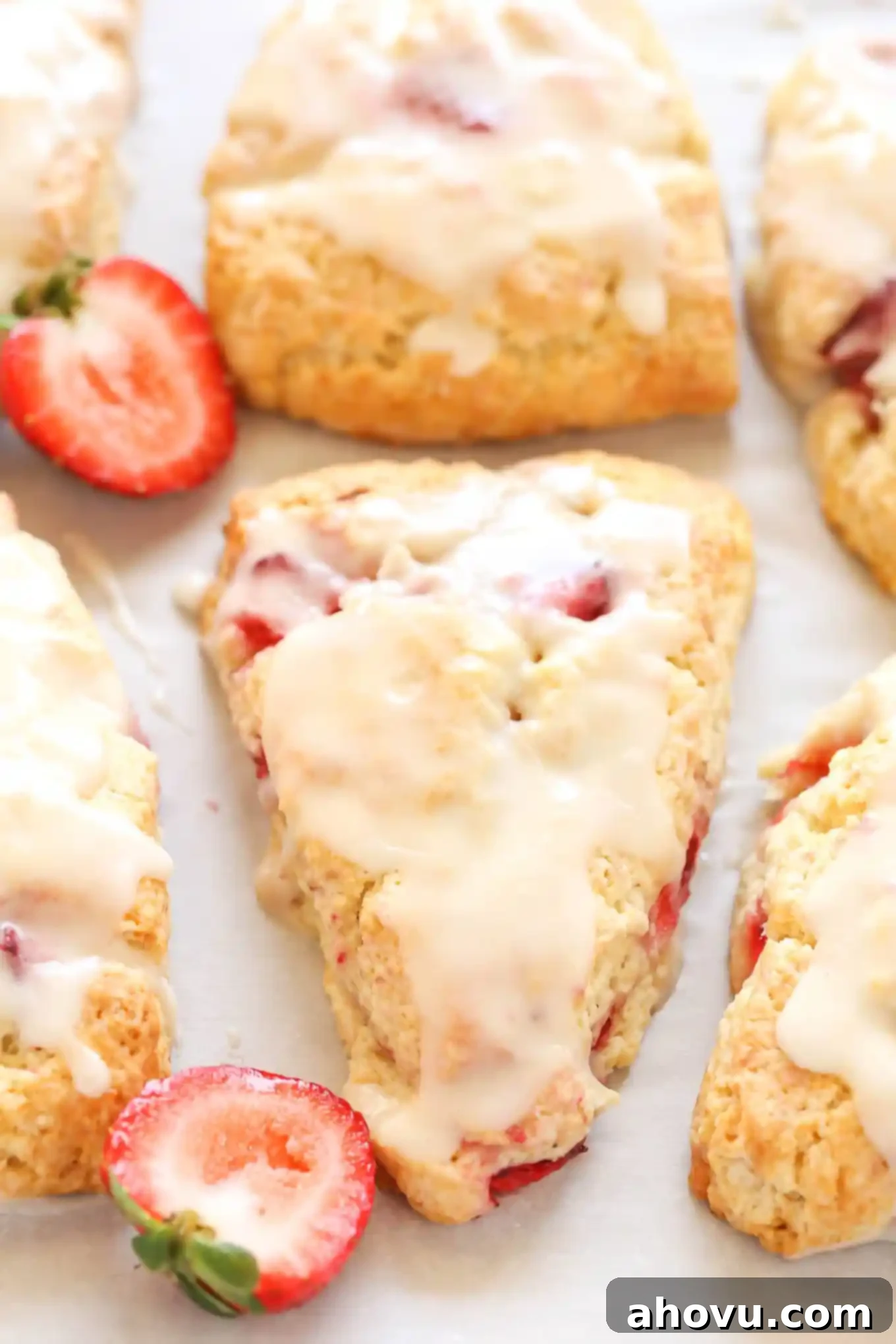 Homemade Strawberry Cream Scones 2 Six glazed strawberry scones with fresh strawberry halves arranged artfully around them, showcasing their delicious appeal.