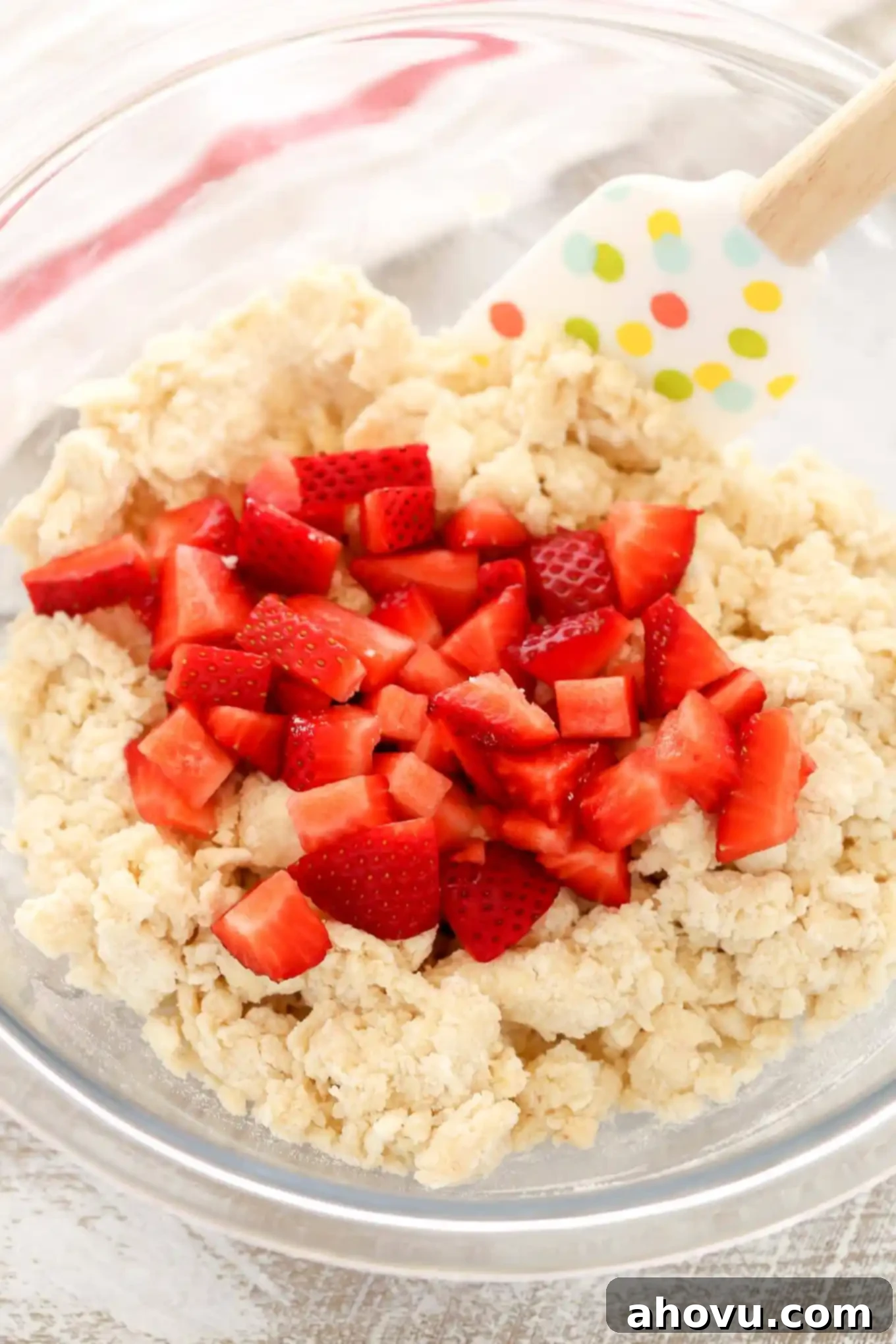 Homemade Strawberry Cream Scones 4 Chopped fresh strawberries are scattered over scone dough in a glass mixing bowl, ready to be gently folded in.