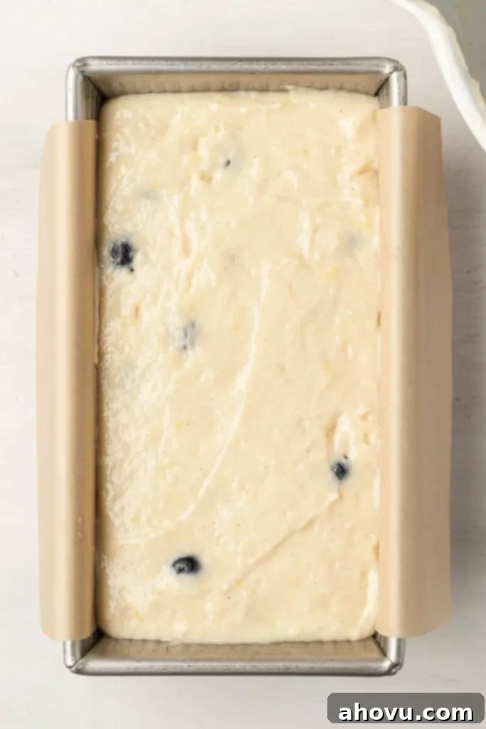 An overhead view of an unbaked lemon blueberry bread batter in a lined 9x5-inch loaf pan, ready to go into the oven.
